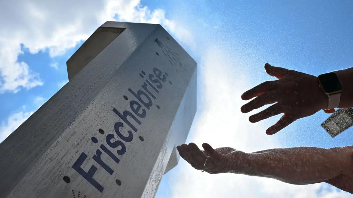 Hitzeaktionsplan für Sachsen: ARCHIV - 13.07.2026, Sachsen, Dresden: Eine Frau kühlt sich in der Dresdner Altstadt an einer Nebeldusche mit Wasser ab. (zu dpa: «Klimazwillinge: Deutsche Städte auf Mittelmeer-Kurs») Foto: Katharina Kausche/dpa +++ dpa-Bildfunk +++