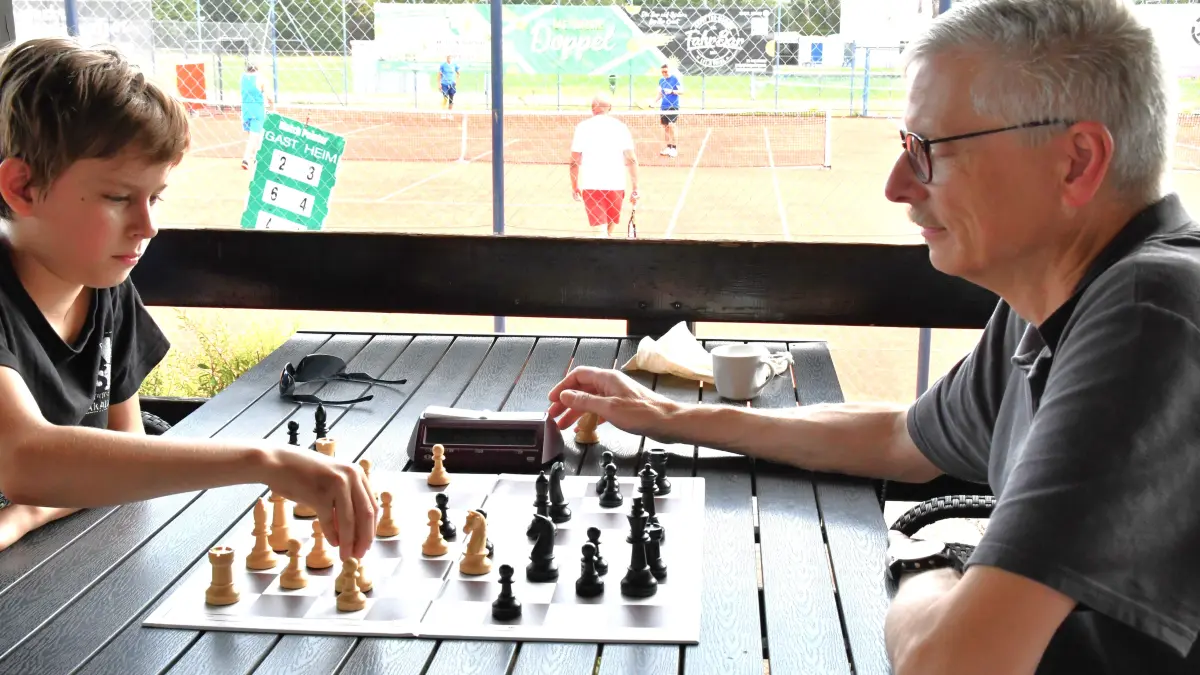 Der Vorsitzende des Schachclubs Brombach Markus Haag am Schachbrett, im Hintergrund wird Tennis gespielt.