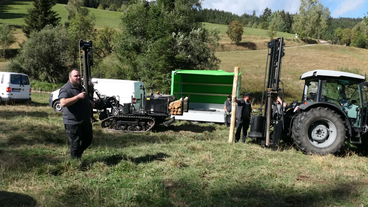 Florian Armbruster zeigt mit Mitarbeitern das Einschlagen von Pfählen für Festzäune.