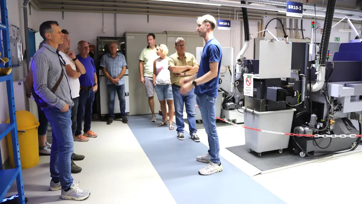 Fabian Fehrenbach (rechts) führt ein gutes Dutzend Besucherinnen und Besucher anlässlich des Tages der offenen Tür durch die Produktion
