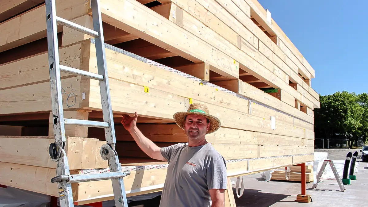 Zimmermann Martin Mahler zeigt einen der 32 Zentimeter hohen Vollholzbalken für die Decken. Der Transport zur Baustelle erfolgte per Sondergenehmigung bereits in den frühen Morgenstunden.