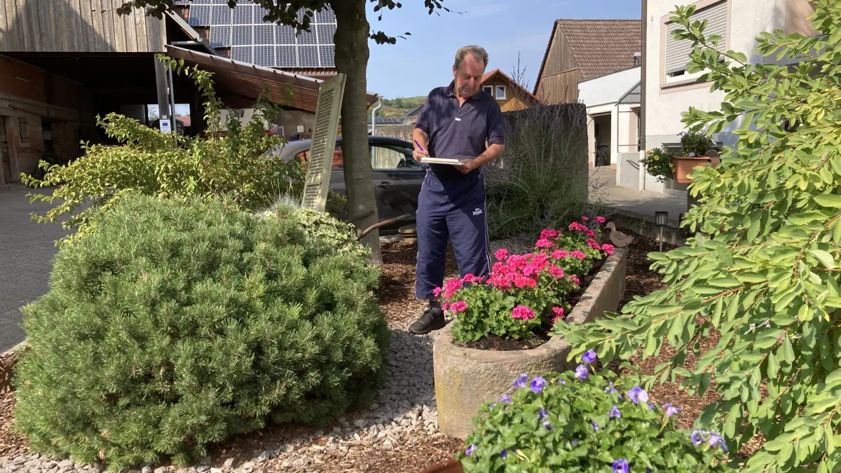 Lothar Füner, Vorsitzender des Obst- und Gartenbauvereins, begutachtet und bewertet den Vorgarten von Tanja und Friedrich Killius in der Friesenheimer Hauptstraße.