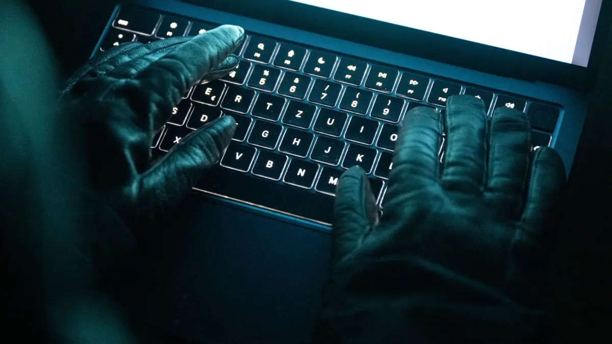 Cyberkriminalität: ILLUSTRATION - 14.12.2025, NA, Berlin: Eine Person tippt mit behandschuhten Händen auf einer beleuchteten Laptop-Tastatur. (Gestellte Szene) (zu dpa: «IT-Experte wirft Berlin «grobe Fahrlässigkeit» vor») Foto: Philip Dulian/dpa +++ dpa-Bildfunk +++