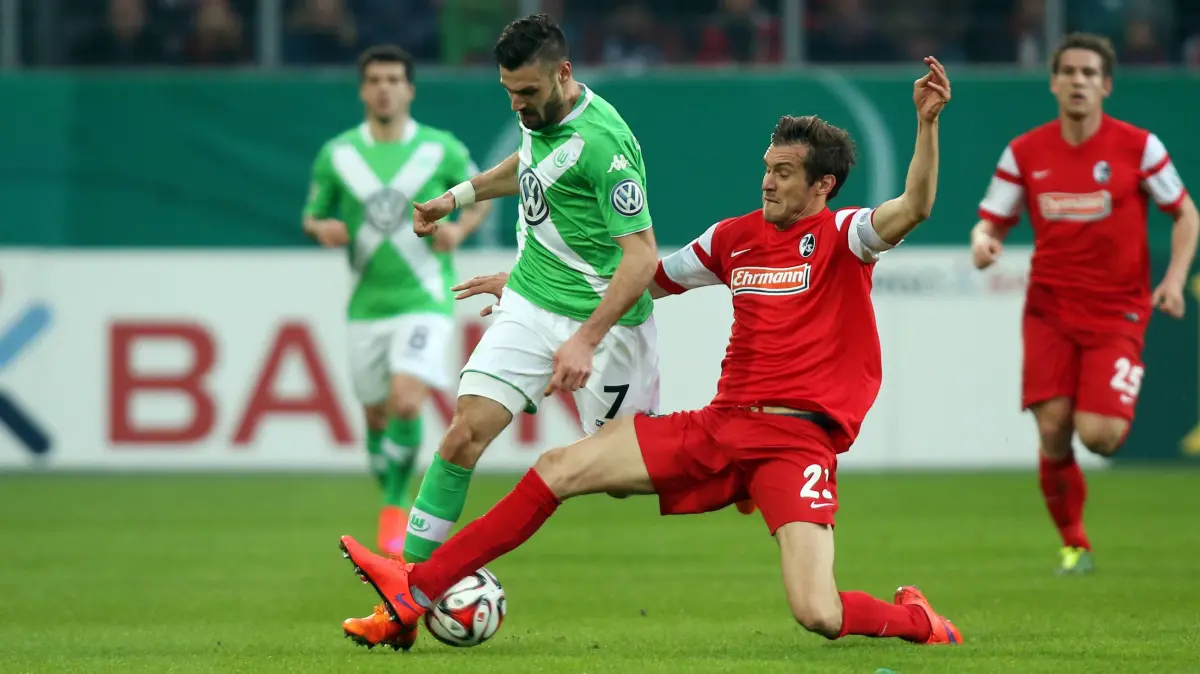 Beim letzten Pokal-Duell mit dem VfL Wolfsburg war der heutige Trainer Julian Schuster (rechts) – hier im Zweikampf mit Daniel Caligiuri – noch Kapitän des SC Freiburg.