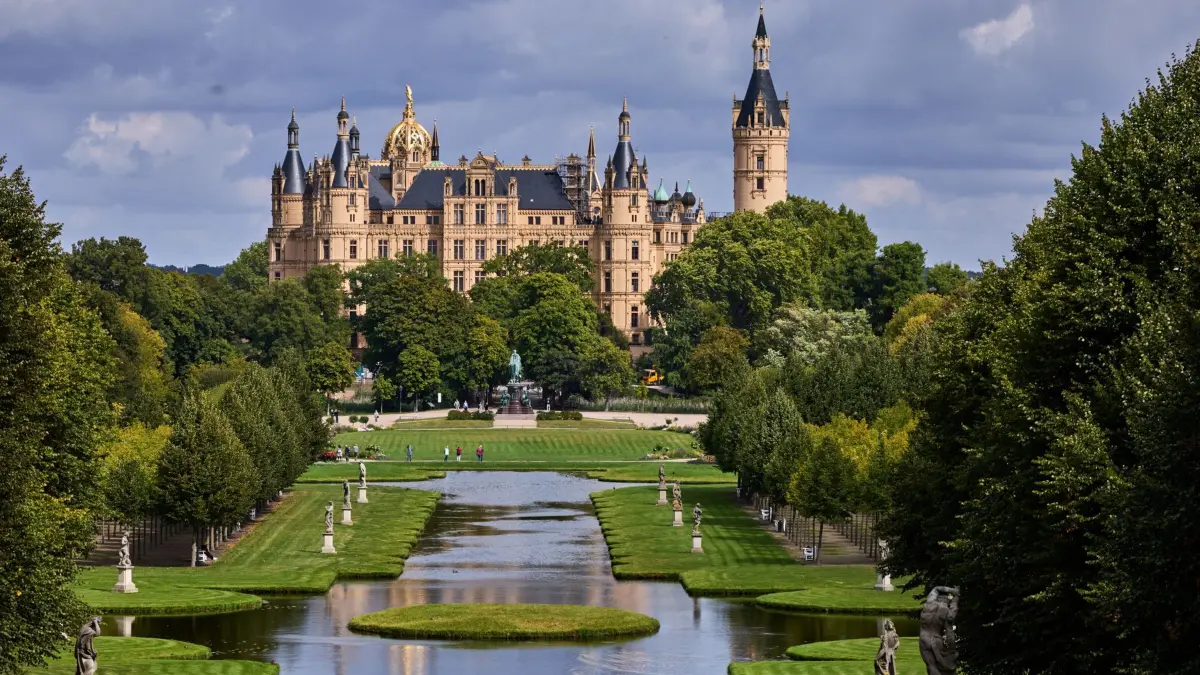 Wetter in Mecklenburg-Vorpommern: 09.09.2026, Mecklenburg-Vorpommern, Schwerin: Ein Radfahrer ist im Schlosspark unterwegs während der Landtagssitz von Mecklenburg-Vorpommern im Schweriner Schloss von der Sonnen angeleuchtet wird. Foto: Jens Büttner/dpa +++ dpa-Bildfunk +++