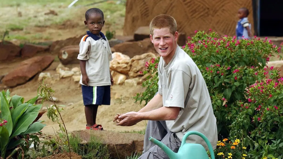 Prinz Harry (l) und der vier Jahre alt Waise Mutsu Potsane pflanzen am 03.03.2004 auf dem Gelände des Mants'ase Kinderheims in Mohale Hoek bei Maseru im Königreich Lesotho einen Pfirsichbaum. Prinz Harry hat mit einem Fernsehteam einen Film über Aids-Waisen in Afrika gedreht. Einen Teil der Bilder habe Harry selbst mit seiner Videokamera aufgenommen, teilte das Büro seines Vaters in London mit. Der Prinz hatte in diesem Jahr acht Wochen in dem südafrikanischen Land Lesotho verbracht, wo etwa 40 Prozent der Bevölkerung mit HIV infiziert sind.