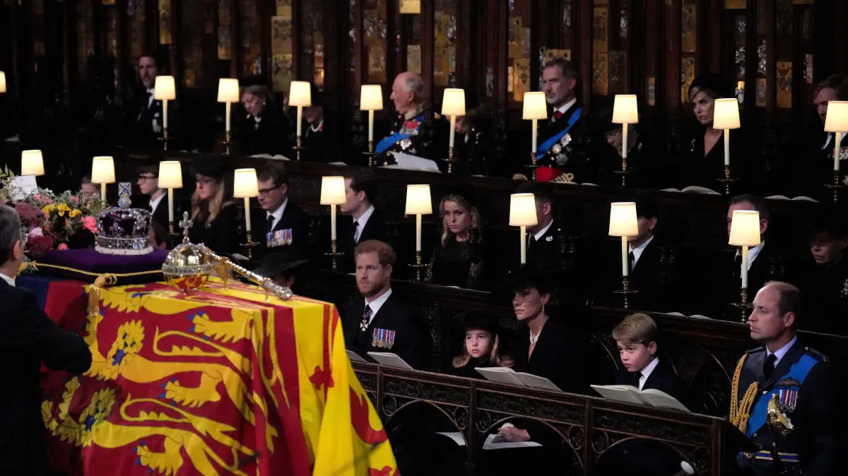 Prinz Harry (vorne l-r), Prinzessin Charlotte, Kate, Prinz George und Prinz William sehen zu, wie die Krone, Reichsapfel und das Zepter während der Beisetzung in der St. Georges Kapelle vom Sarg von Königin Elizabeth II. abgenommen werden.