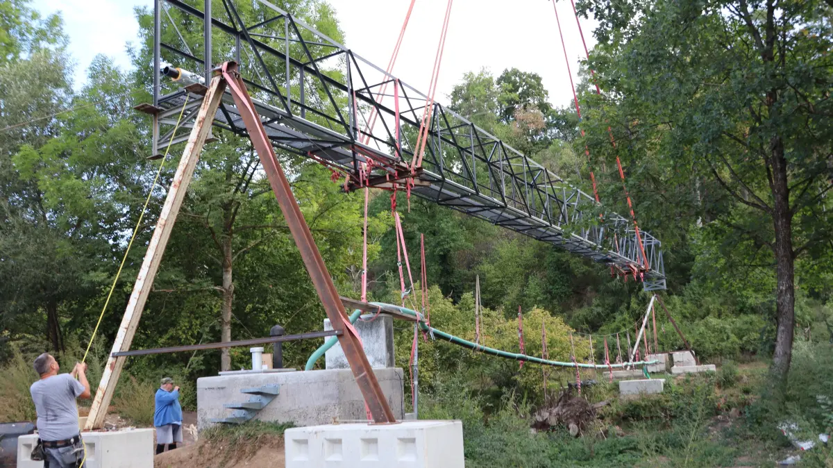 Durch Gebüsch und Bäume ist die sanierte Brücke fast schon am alten Platz.