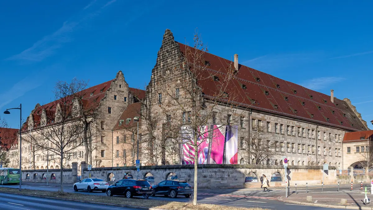 Außenansicht des historischen Justizgebäudes in der Fürther Straße in Nürnberg mit markanten Giebeln und rotem Satteldach. In dem Gebäude befinden sich unter anderem die Schwurgerichtssäle, darunter auch der Saal 600, bekannt durch die Nürnberger Prozesse.