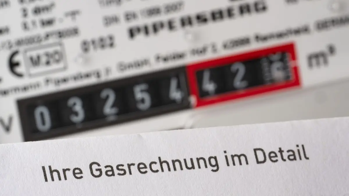 Eine Gasrechnung wird in einem privaten Haushalt vor einem Gaszähler gehalten (gestellte Szene).