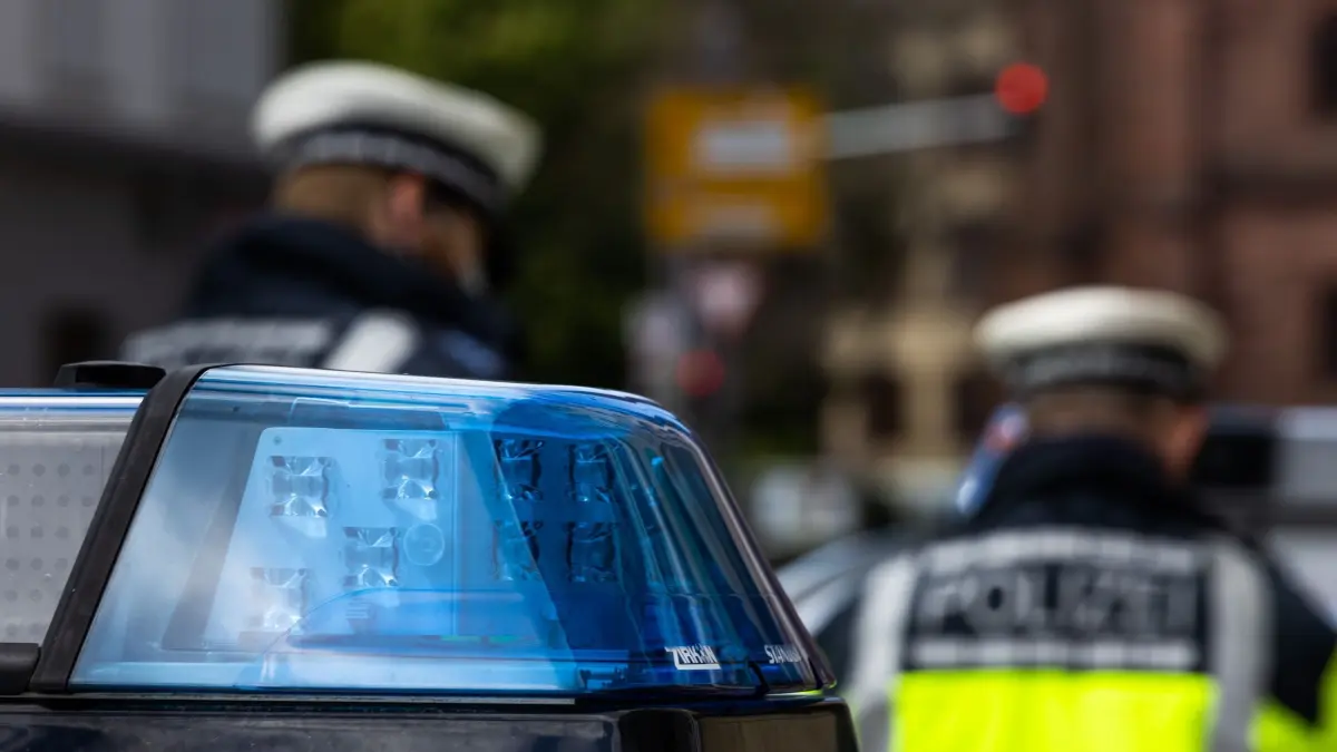 Symbolbild - Polizei: Zwei Polizeibeamte stehen zwischen zwei Einsatzfahrzeugen der Polizei. (zu dpa: «Einbrecher stehlen Hunderte Kilo schweren Tresor»)