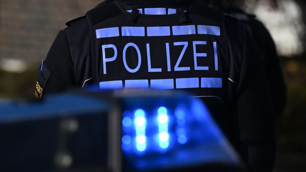 Polizei: ARCHIV - 03.12.2024, Baden-Württemberg, Stuttgart: Das Logo der Polizei auf der Dienstkleidung eines Polizisten der vor einem Blaulicht steht (gestellte Szene). (zu dpa: «Bekannte sollen 19-Jährigen geschlagen und gedemütigt haben») Foto: Bernd Weißbrod/dpa +++ dpa-Bildfunk +++