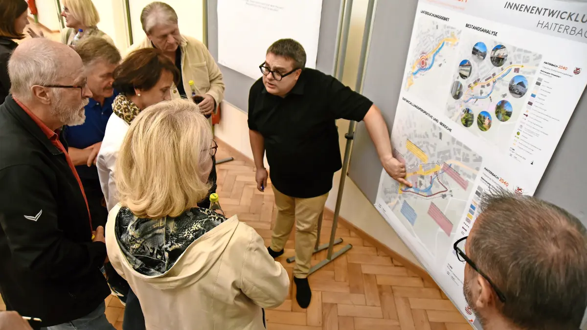 Philipp König vom Büro Reschl diskutiert mit Teilnehmern an einer Infotafel.