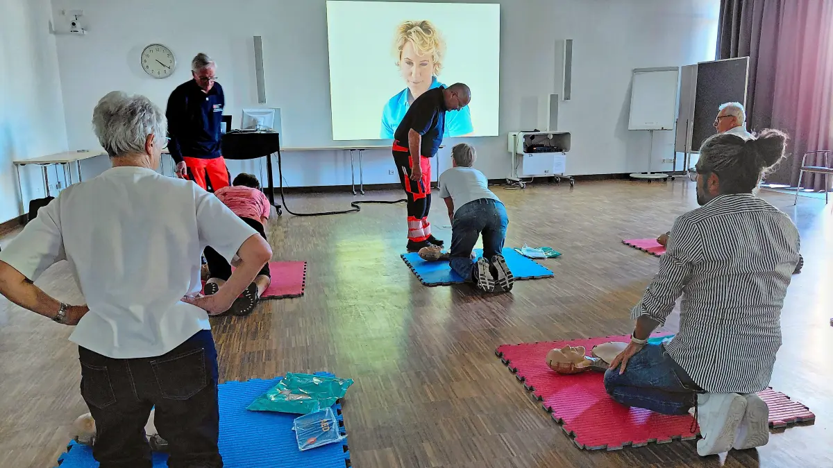 Kardiologe Dr. Johannes Kohler (links vorne) und Rettungssanitäter Thomas Kienzler leiten mit Videodame Tina die Teilnehmer zur Notfallhilfe beim Kurzkurs im Baden-Württemberg-Saal des Klinikums an.