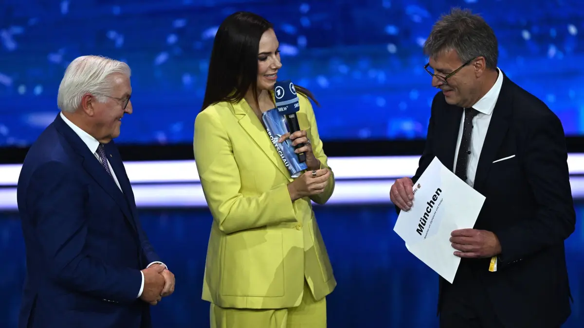 DOSB wählt deutschen Olympia-Bewerber: 26.09.2026, Baden-Württemberg, Baden-Baden: Sportpolitik: Frank-Walter Steinmeier (l-r), Bundespräsident der Bundesrepublik Deutschland, Moderatorin Esther Sedlaczek und Thomas Weikert, Präsident des Deutschen Olympischen Sportbundes (DOSB), öffnen auf der Bühne bei der außerordentlichen DOSB-Mitgliederversammlung zur Wahl des deutschen Olympia-Bewerbers für 2036, 2040 oder 2044 den Umschlag. München ist der deutsche Kandidat für Olympia und Paralympics für 2036, 2040 oder 2044. Foto: Marijan Murat/dpa +++ dpa-Bildfunk +++