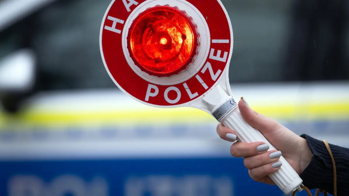 Halt! Polizei!: Eine Polizistin hält während einer Verkehrskontrolle eine Polizeikelle mit der Aufschrift „Halt Polizei“. (Symbolbild) (zu dpa: «Lkw mit Papier-Kennzeichen - Polizei stoppt Fahrer»)