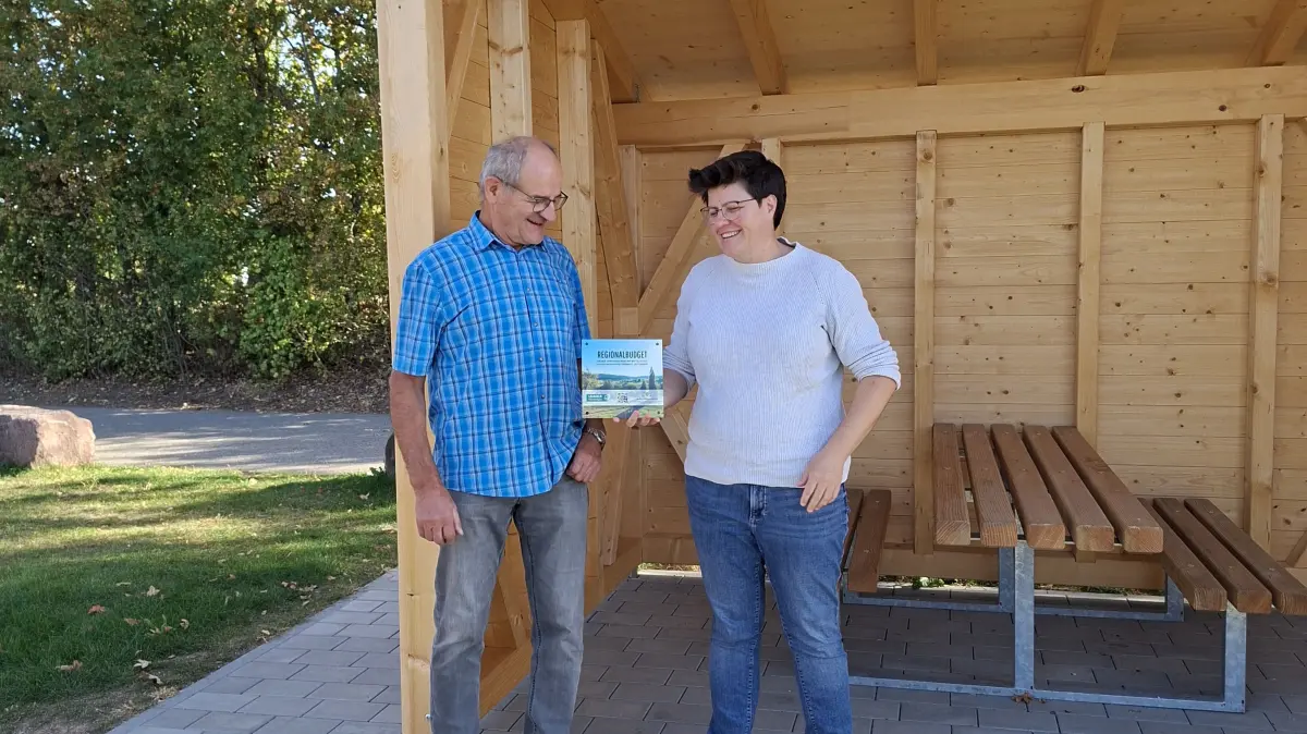 Ortsvorsteher Hartmut Weber und Susann Bauer von Leader Heckengäu am neuen Unterstand.