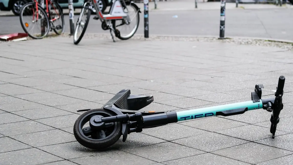E-Scooter: Ein E-Scooter liegt umgekippt mitten auf einem Gehweg. (zu dpa: «Zu zweit auf dem E-Scooter - Duo bei Sturz schwer verletzt»)