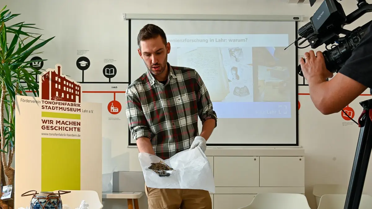 Bastian Kussin, der das Forschungsprojekt leitet, zeigt die Sammlungsgegenstände.