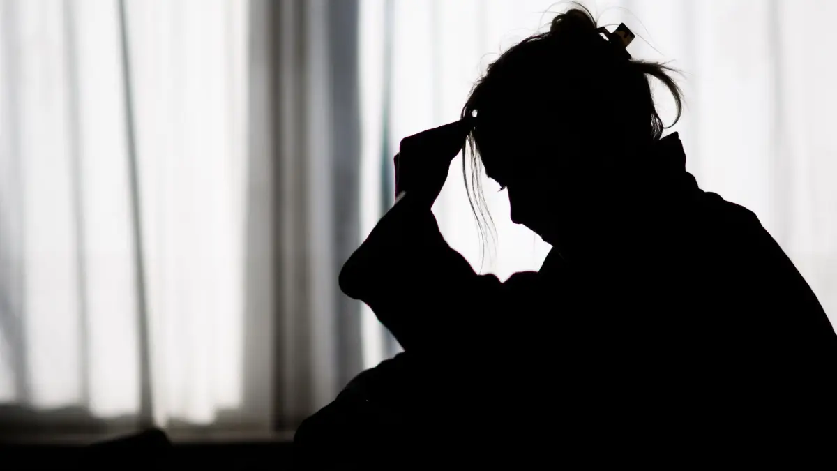 Psychische Belastung nimmt in Deutschland zu : Die Silhouette einer Frau zeichnet sich vor einer hellen Fensterfront ab (gestellte Szene). (zu dpa: «Psychische Gesundheit: Wie sehr belastet uns die Dauerkrise?»)
