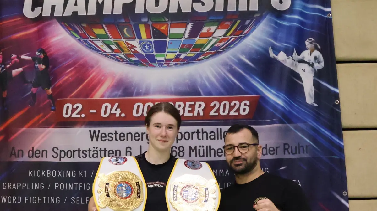 Laura Schmieder präsentiert ihre beiden Weltmeistergürtel. Stolz ist auch ihr Trainer Berhan Keles.