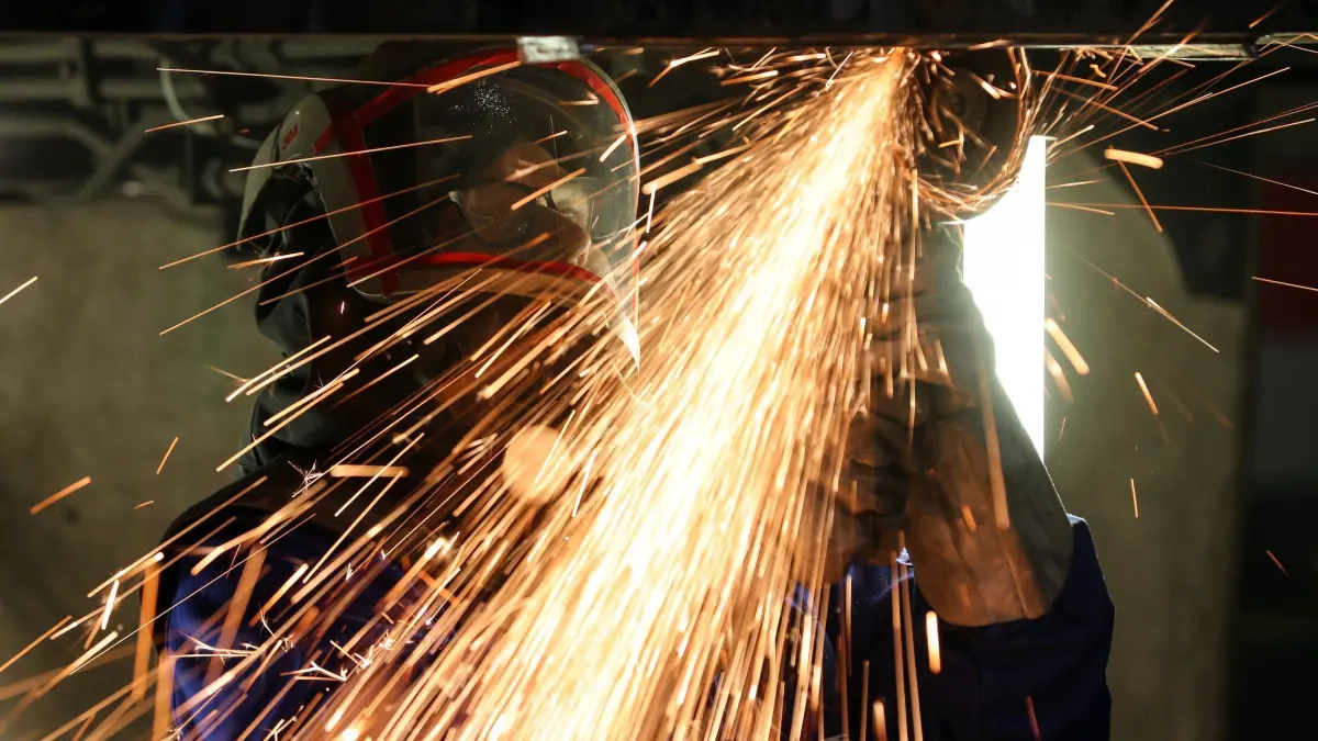 Maschinenbauer: Ein Mitarbeiter eines Maschinenbauers schneidet mit einem Trennschleifer korrodierte Metallteile aus dem Träger in einem Wagenkasten. (zu dpa: «Industrie-Auftragseingang sinkt überraschend deutlich»)