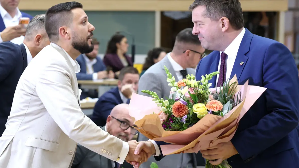 GERMANY-POLITICS-VOTE-STATE-PARLIAMENT-DEMO: Conservative Christian Democratic Union's (CDU) Sven Schulze gives flowers to Far-right Alternative for Germany (AfD)'s Tobias Rausch to congratulate him on his election as president of the state parliament as AfD's Ulrich Siegmund looks on during the first constituent session of the state parliament of Saxony-Anhalt in Magdeburg, eastern Germany, on October 6, 2026. Newly elected state lawmakers will gather for the first time in the parliament building in the state capital Magdeburg to elect a speaker, with a candidate of the far-right Alternative for Germany (AfD) expected to win. The AfD is poised to preside over a state assembly for the first time following its landslide election victory in the eastern state of Saxony-Anhalt. The AfD took nearly 44 percent of the vote in the September 2026 state election. (Photo by Jan Woitas / POOL / AFP)
