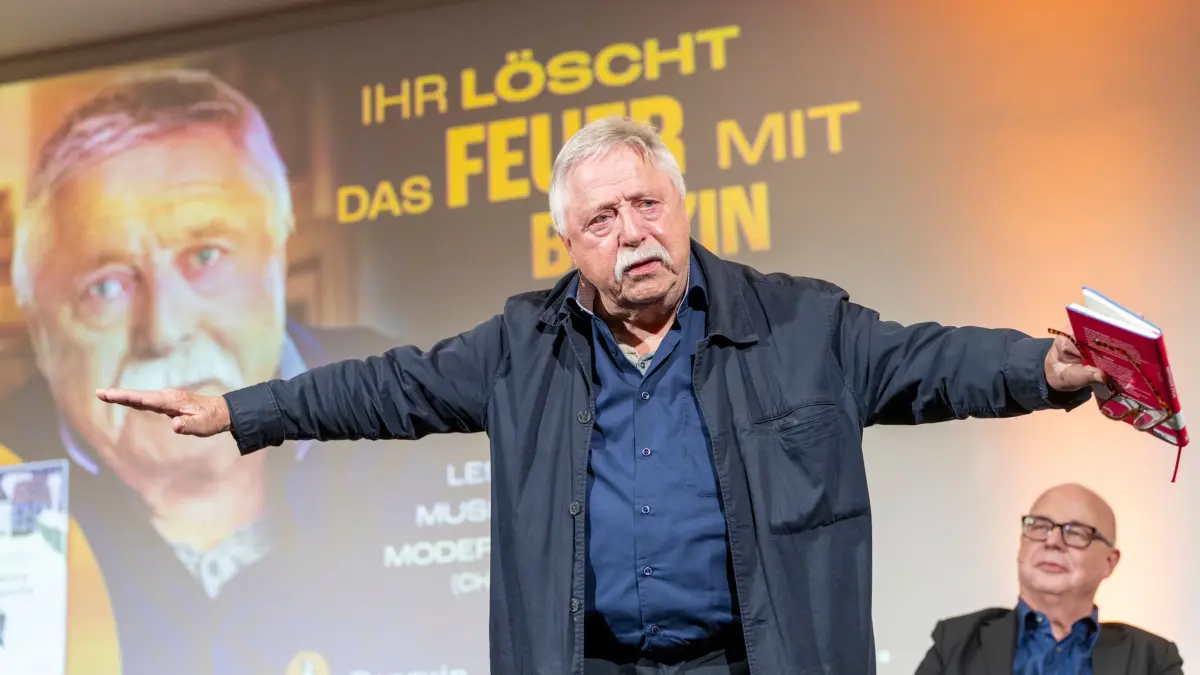 Fortsetzung 78. Frankfurter Buchmesse: 07.10.2026, Hessen, Frankfurt am Main: Wolf Biermann (l), Liedermacher und Lyriker, steht auf der Bühne und hält dabei sein Buch "Mit uralten Kinderaugen" in der Hand. Im Hintergrund sitzt Sven Gösmann, dpa-Chefredakteur und Moderator des Abends. Im Rahmen der Buchmesse findet die Veranstaltung "Ihr löscht das Feuer mit Benzin - Ein Abend mit Wolf Biermann" statt. (zu dpa: «Wolf Biermann live - «Es berührt mich, wie blöde ich war»») Foto: Andreas Arnold/dpa +++ dpa-Bildfunk +++