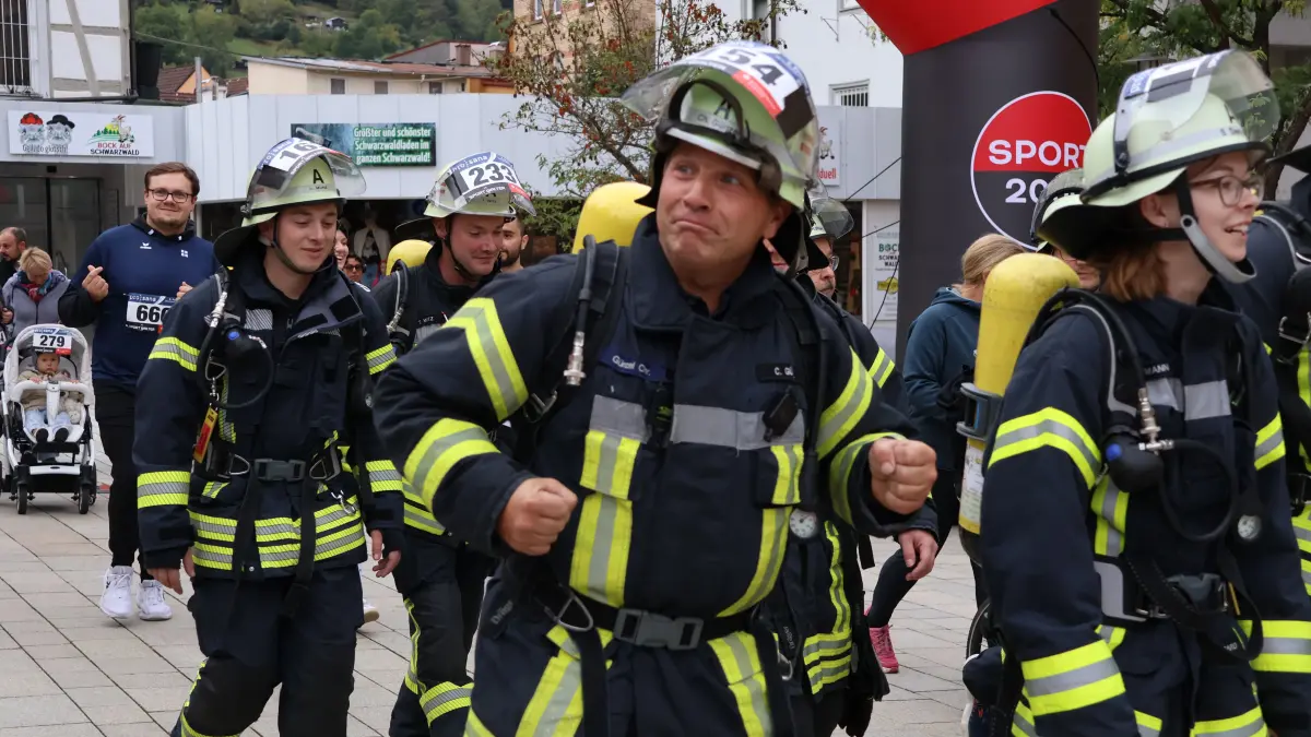 Mitglieder der Feuerwehr laufen in voller Montur mit.