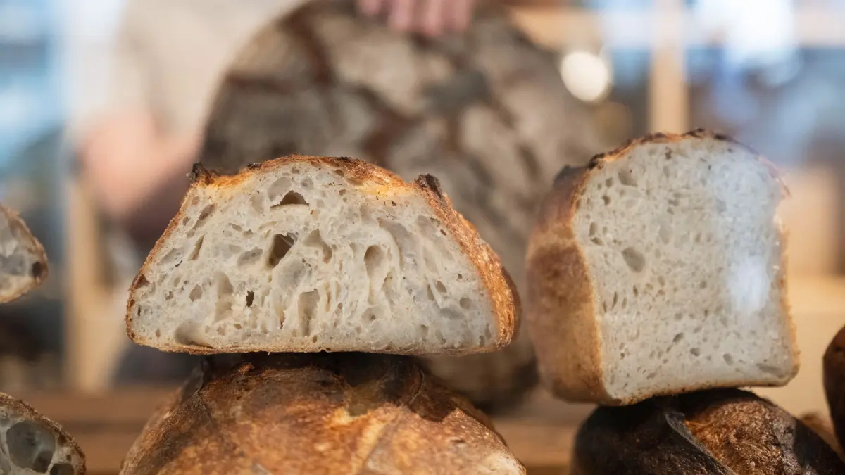 PRODUKTION - 02.10.2025, Baden-Württemberg, Stuttgart: Sophie Henne, Inhaberin der Sauerteigbäckerei Brotique, schneidet ein Sauerteig-Brot auf der Verkaufstheke. (zu dpa: «Taylor-Swift-Effekt? Sauerteig auf Höhenflug») Foto: Marijan Murat/dpa +++ dpa-Bildfunk +++