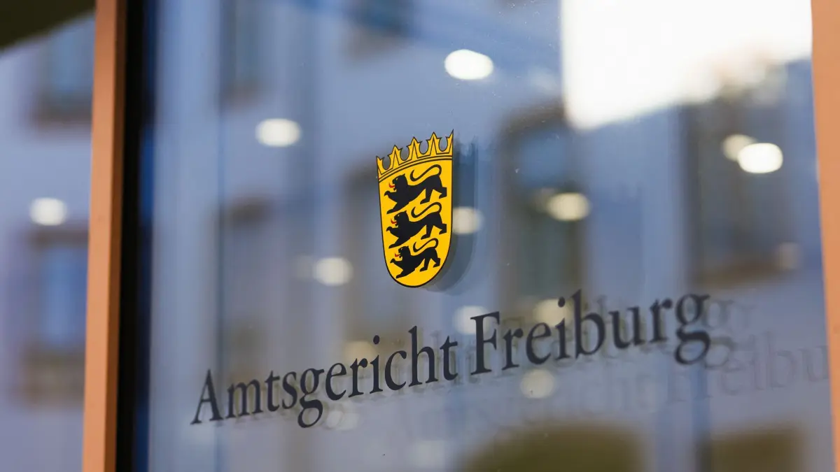 Beginn Prozess gegen Ehepaar u.a. wegen Störung der Totenruhe: 12.10.2026, Baden-Württemberg, Freiburg: Der Schriftzug "Amtsgericht Freiburg" ist auf einer Glasscheibe zu lesen. Einem angeklagten Ehepaar werden neben 50 Fällen von Diebstahl, beziehungsweise wegen Beihilfe, mindestens 250 Fälle vorgeworfen. Der Ehemann war nach Angaben des Gerichts bis Ende Oktober 2024 als Bestatter beim Eigenbetrieb Friedhöfe der Stadt Freiburg angestellt. Ihm wird vorgeworfen, von 2013 an Zahngold von Leichen entwendet zu haben, die verbrannt werden sollten - teilweise mit grober Gewalt. Außerdem soll er den Leichen Schmuck, Uhren und sonstige Wertgegenstände abgenommen haben. Seine Frau soll ihn bei den Taten unterstützt haben. Foto: Philipp von Ditfurth/dpa +++ dpa-Bildfunk +++