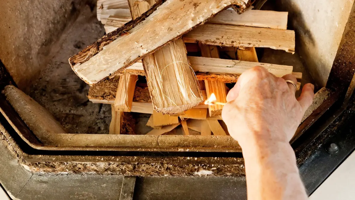 Eine Person zündet einen Kaminofen an: ARCHIV - Trockenes Holz ist entscheidend: Der Feuchtegehalt des Brennholzes darf höchstens 25 Prozent betragen. Foto: Monique Wüstenhagen/dpa-mag - Honorarfrei nur für Bezieher des Dienstes dpa-Magazin +++ dpa-Magazin +++
