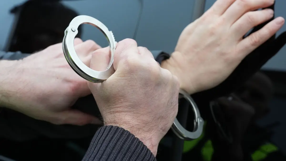 Festnahme Symbolbild: ARCHIV - 11.12.2024, Schleswig-Holstein, Kiel: Ein Polizist legt einem Mann Handschellen an. (Symbolfoto) (zu dpa: «Waffen, Kokain und Bargeld entdeckt - zwei Männer in Haft») Foto: Marcus Brandt/dpa +++ dpa-Bildfunk +++