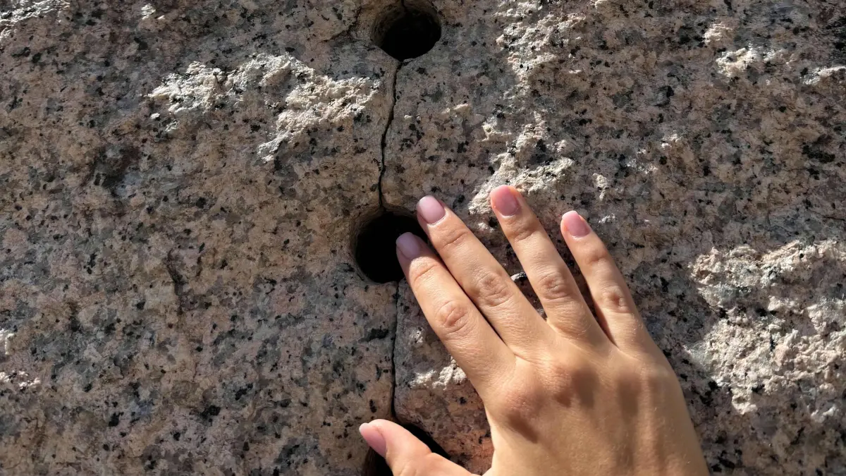 Hand auf der Skulptur des Rückriem-Würfels auf dem Lörracher Marktplatz.
