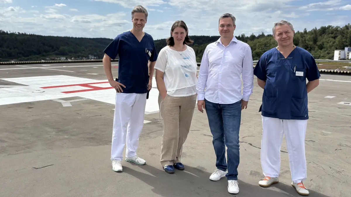 Auf dem Hubschrauberlandeplatz der Kliniken Nagold begrüßen Prof. Dr. Daniel Kauff (links), Klinikdirektorin Alexandra Freimuth (daneben) und Herr Batura (rechts) den künftigen Sektionsleiter der Unfallchirurgie, Dr. Aljoscha Schäffler, im Team des Klinikverbunds Südwest.