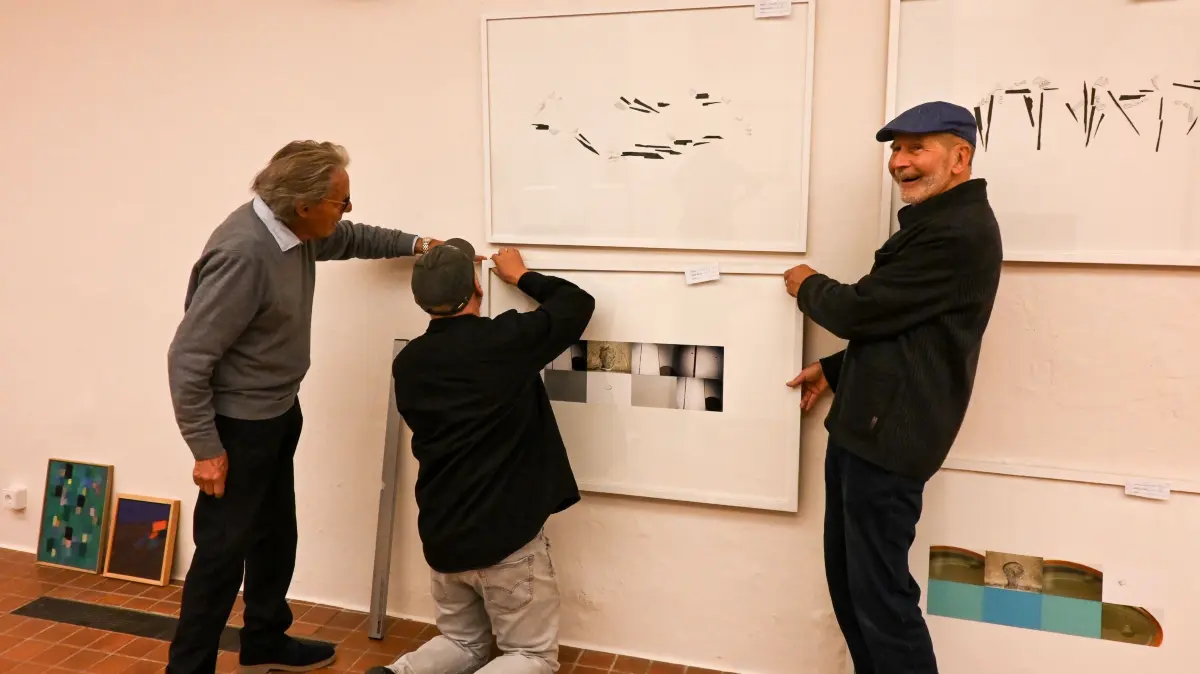 Der Vorsitzende des Kunstvereins VS, Helmut Kury (links), und Geschäftsführer Bernhard Fabry (rechts) packen mit an und helfen Reinhard Sigle beim Aufhängen.