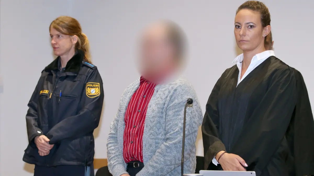 Prozessauftakt wegen Mordes an Ehefrau - 214841762 DPA Ein Angeklagter (M) steht neben seiner Anwältin Martina Sulzberger (r) in einen Gerichtssaal des Strafjustizzentrums. Der Bauer aus Nordschwaben steht seit Dienstag vor dem Landgericht Augsburg, weil er seine Ehefrau bewusstlos geschlagen und sie dann mit Gülle übergossen haben soll, bis sie erstickte. Der Mann bestreitet die Tat. +++ dpa-Bildfunk +++