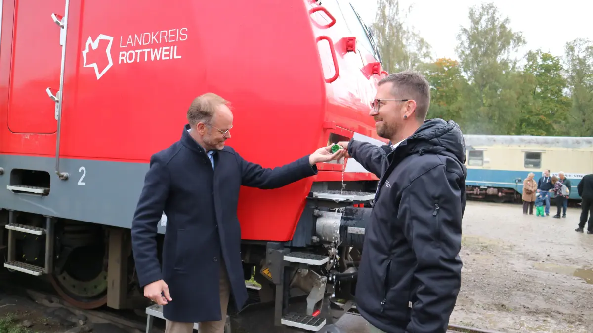 Andreas Kaupp, Geschäftsführer der NESA (rechts), und Landrat Christoph Keckeisen sorgen mit einem Piccolo für die standesgemäße Loktaufe.