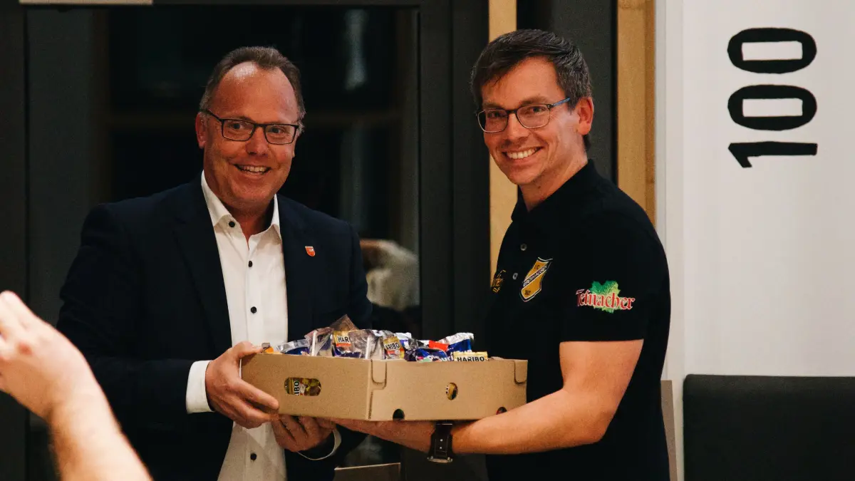 Bürgermeister Sven Holder überreicht ein Geschenk an Benjamin Finis