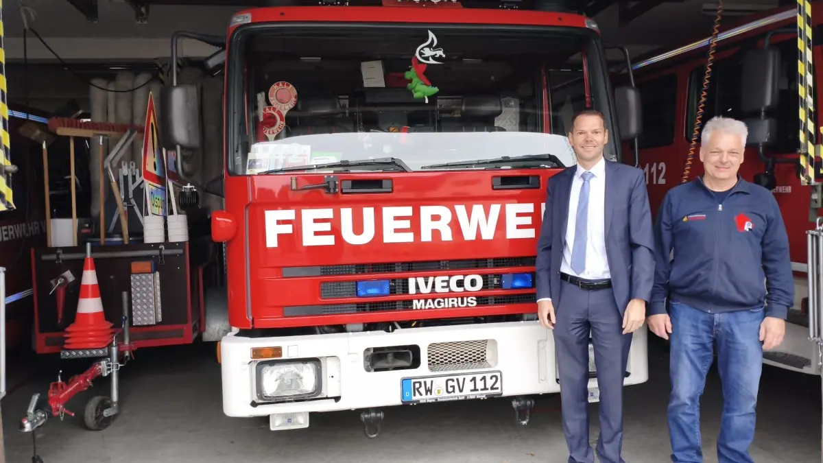 Bürgermeister Marcus Türk (links) und Feuerwehrkommandant Robert Flaig im Feuerwehrhaus. Das Foto dokumentiert die räumliche Enge in der Fahrzeughalle, die keine gesetzlich vorgeschriebenen Sicherheitsabstände zwischen den Fahrzeugen zulässt.