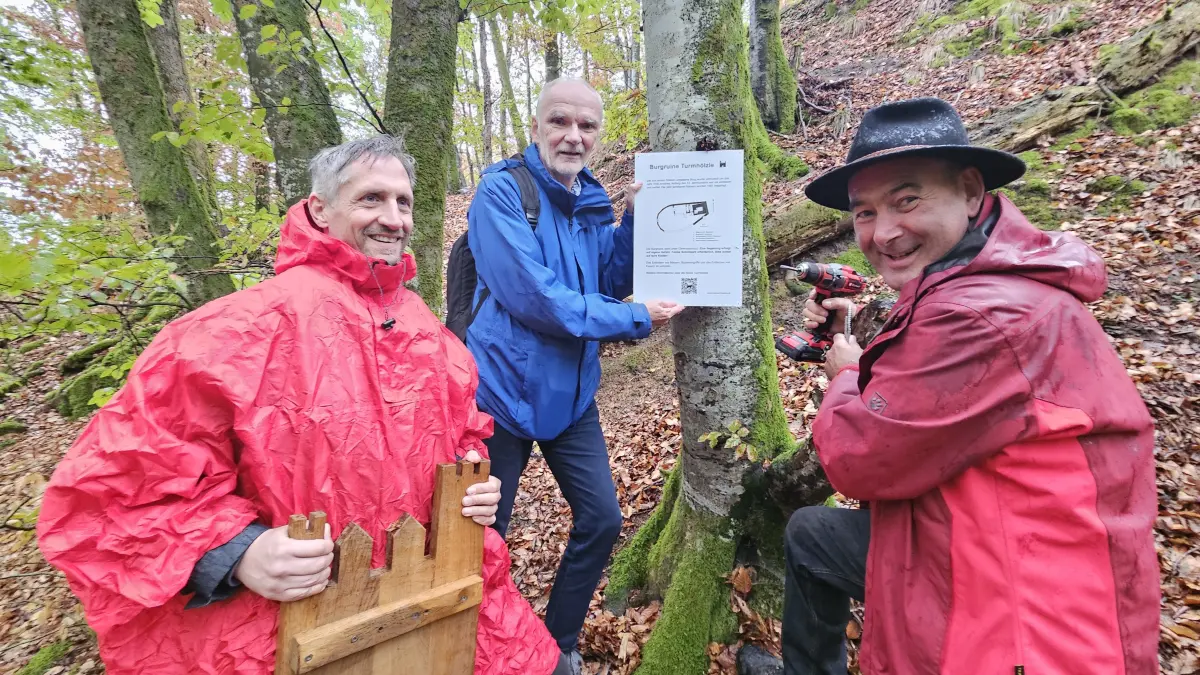 Dominik Baiker, Wolfgang Richter und Thomas Dattler (von links) bringen eine Infotafel am Fuße der Burgruine Turmhölzle in Raitbach an.