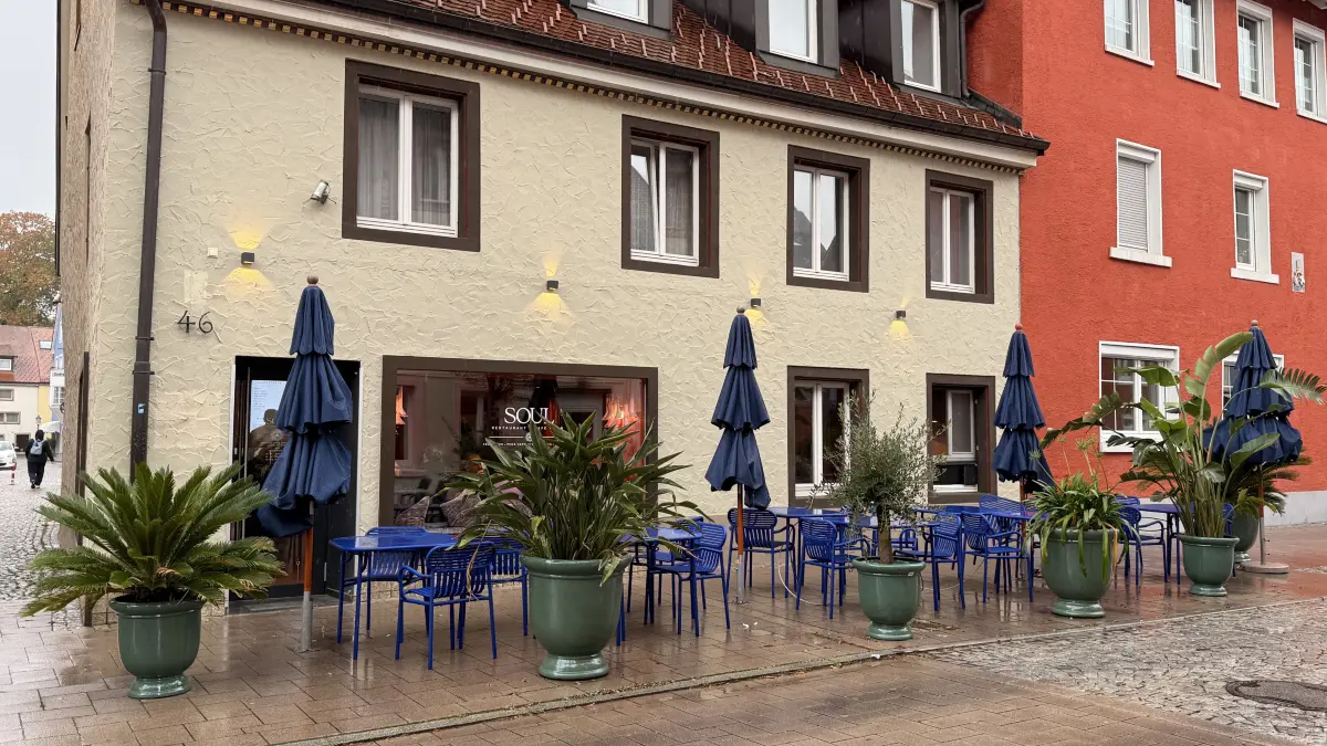 Von außen eher zurückhaltend, vor dem Lokal setzen blaue Möbel und Sonnenschirme jedoch einen markanten Farbakzent.