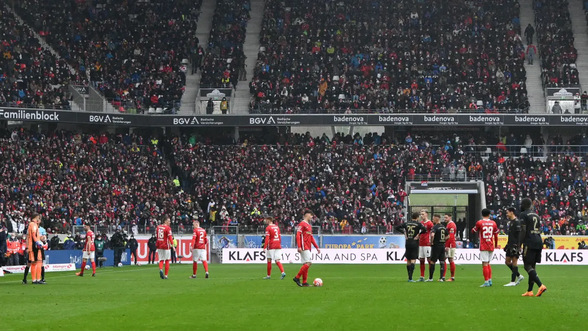 02.04.2022, Baden-Württemberg, Freiburg im Breisgau: Fußball: Bundesliga, SC Freiburg - Bayern München, 28. Spieltag im Europa-Park Stadion. Die Spieler von Freiburg (rote Trikots) und Bayern stehen während einer längeren Unterbrechung während des Spiels auf dem Platz. Foto: Silas Stein/dpa - WICHTIGER HINWEIS: Gemäß den Vorgaben der DFL Deutsche Fußball Liga bzw. des DFB Deutscher Fußball-Bund ist es untersagt, in dem Stadion und/oder vom Spiel angefertigte Fotoaufnahmen in Form von Sequenzbildern und/oder videoähnlichen Fotostrecken zu verwerten bzw. verwerten zu lassen. +++ dpa-Bildfunk +++