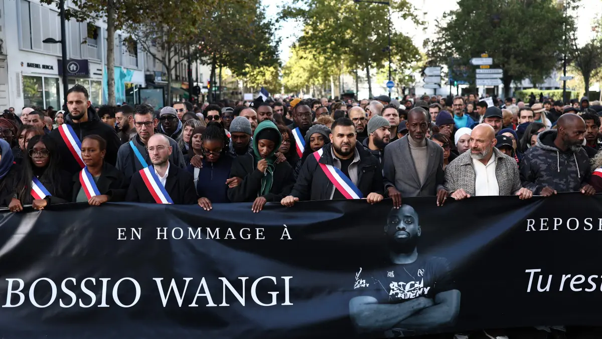 FRANCE-CRIME-POLITICS-CEREMONY-DEMO: Attendees and officials including mayor of Aubervilliers Sofienne Karroumi (C) and Saint-Denis Mayor Bally Bagayoko take part in a silent march in tribute to Pengo Bossio Wangi, a man killed in a shooting by an attacker on October 23, a march organised by his MMA club near the town hall of Aubervilliers, north of Paris, on October 25, 2026. A man suspected of a gun attack in the Paris suburbs that killed Pengo Bossio Wangi and wounded five other persons has left custody and been placed in a psychiatric unit for observation, French anti-terror prosecutors said on October 25, 2026. The 39-year-old suspect, partly identified as Kevin T., was arrested on October 23, in possession of a submachine gun and tear-gas grenades in his car, shortly after the victims were shot as a vehicle drove through the working-class town of Trappes and neighbouring La Verriere. (Photo by Sameer AL-DOUMY / AFP)