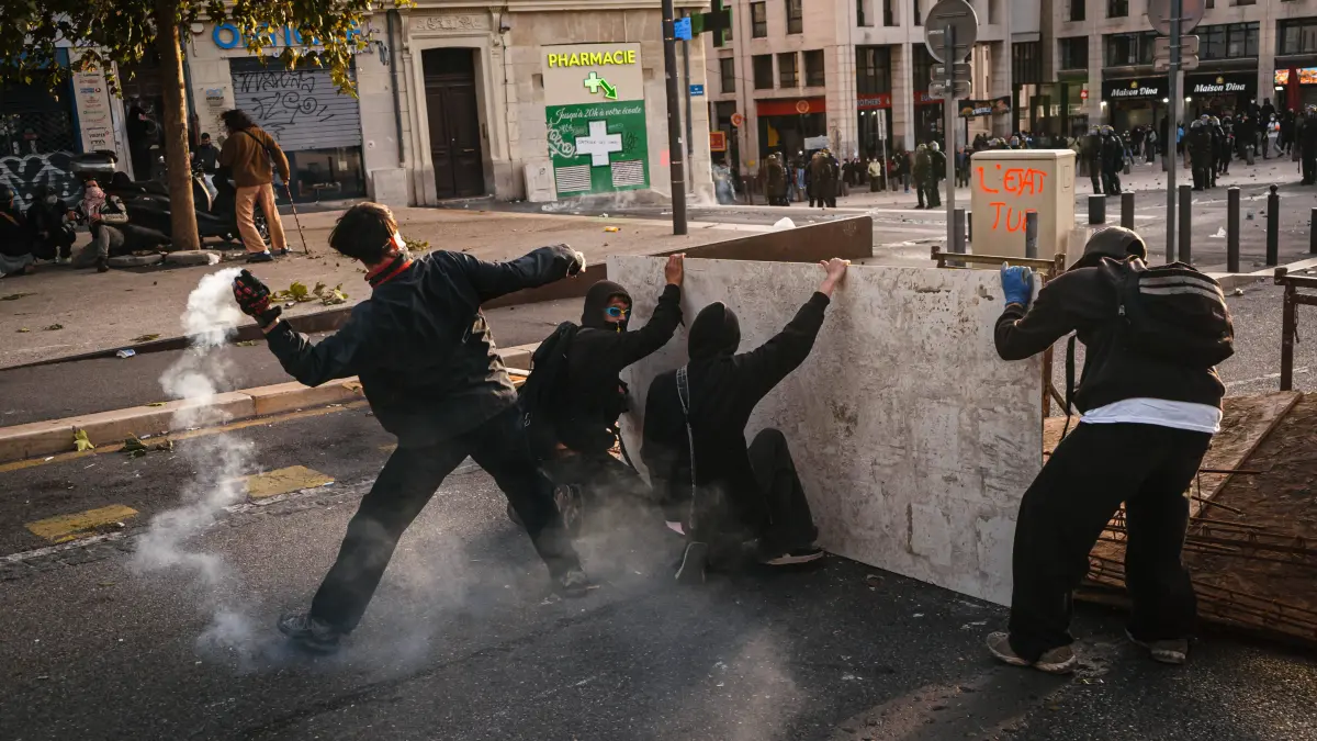 Marseille France Street Protests: Marseille France Street Protests Protesters take cover behind a wooden barrier while a tear gas canister releases smoke during a protest in Marseille, France on October 24, 2026. Authorities deployed around 70,000 security personnel across France for renewed protests over the cost of living, after unrest a week earlier saw public buildings damaged, hundreds of shops looted and about 2,700 people arrested. Marseille Provence-Alpes-CÃ te France Copyright: xNaelxChahinex