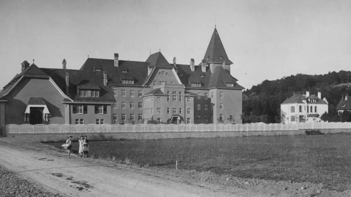 Die neugebaute Realschule (heute Hans-Thoma-Gymnasium) auf dem Niederfeld an der Gemarkungsgrenze zu Stetten; daneben das ehemalige Privatschulgebäude, von 1919 bis 1952 Handelsschule, ab 1960 Kerngebäude des Hebel-Gymnasiums. Im Vordergrund die unbefestigte Kreuzstraße.