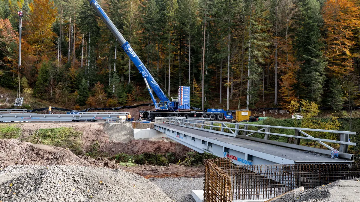 Ein Kran hebt die Einzelteile der Behelfsbrücke an ihren Platz über der Großen Enz.