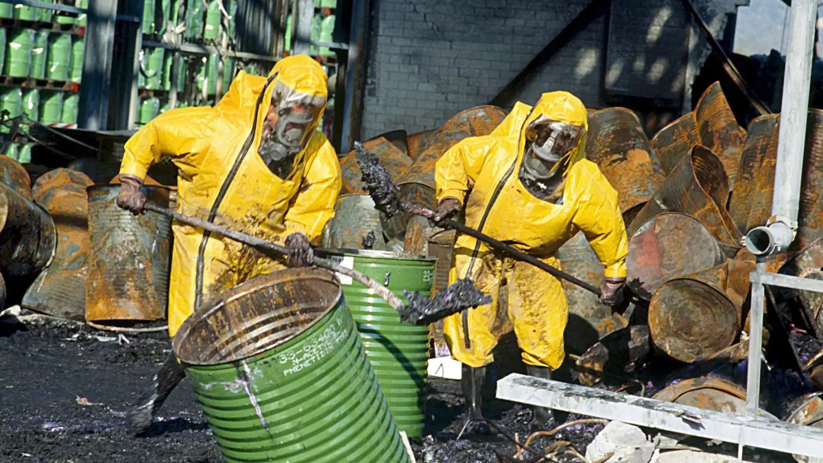 Feuerwehrleute in Schutzkleidung räumen einige Tage nach einem Brand in einem Chemiewerk des Schweizer Chemieunternehmens Sandoz die Trümmer auf.